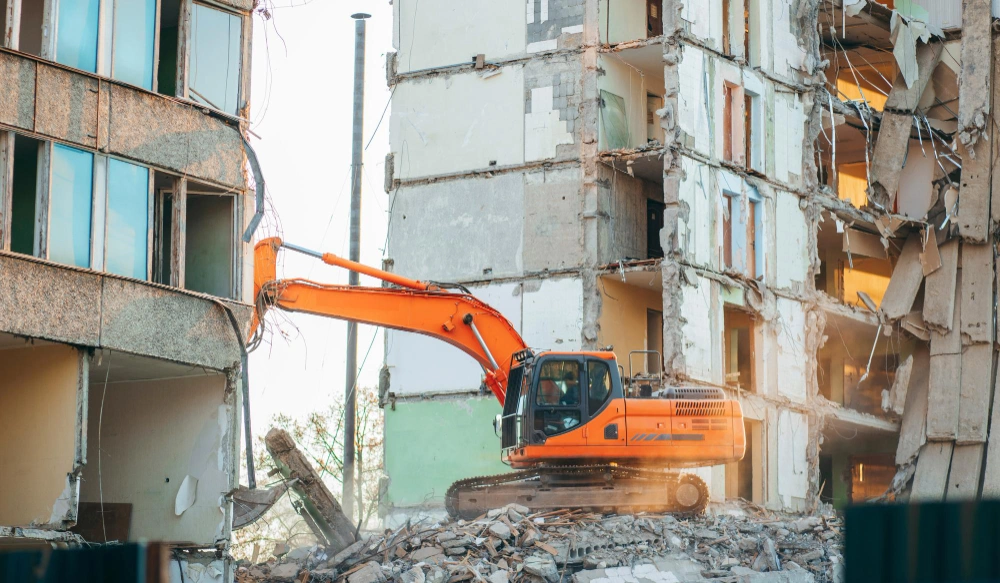 Excavator demolishing residential building during controlled demolition project in Los Angeles