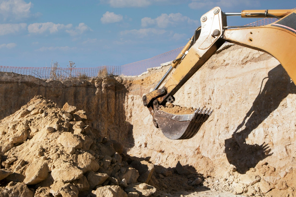 Excavator shaping foundation trench during site excavation project on Los Angeles construction site